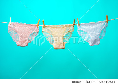 Female panties hanging on rope against blue studio background 95840684