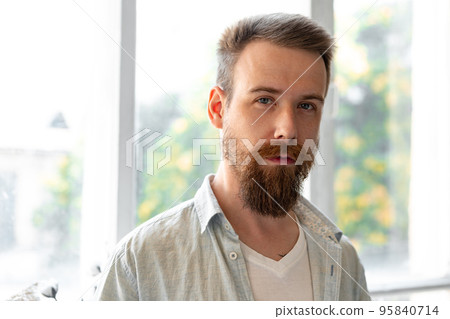 Bearded smiling handsome young man standing alone at home 95840714