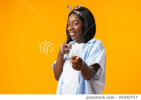 Happy young african lady standing over yellow background while pointing to you Happy young african lady standing over yellow background while pointing to you 95840757