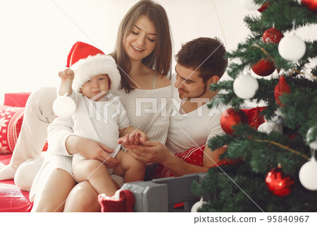 Mother in a white sweater. Family with christmas gifts. Child with parents in a christmas decorations. Mother in a white sweater. Family with christmas gifts. Child with parents in a christmas decorations. 95840967
