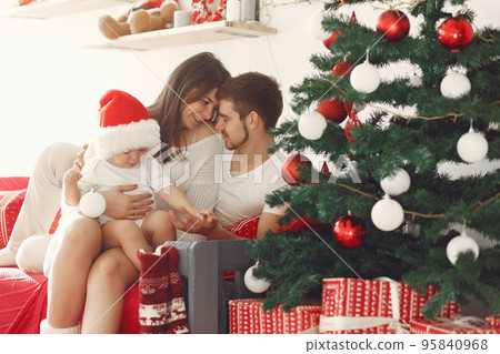 Mother in a white sweater. Family with christmas gifts. Child with parents in a christmas decorations. 95840968