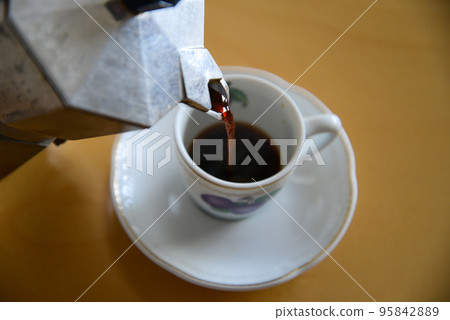 Pour the espresso brewed in the moka pot into the demitasse cup Pour the espresso brewed in the moka pot into the demitasse cup 95842889