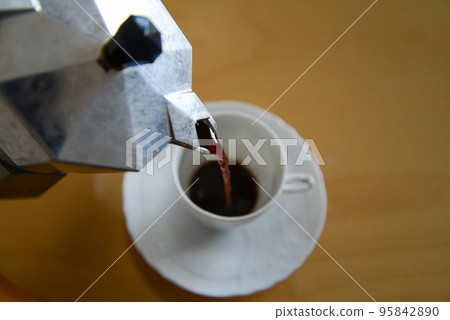 Pour the espresso brewed in the moka pot into the demitasse cup Pour the espresso brewed in the moka pot into the demitasse cup 95842890