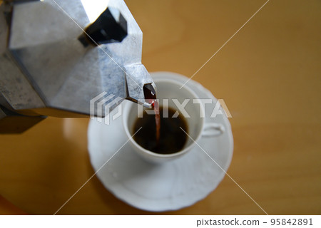 Pour the espresso brewed in the moka pot into the demitasse cup Pour the espresso brewed in the moka pot into the demitasse cup 95842891