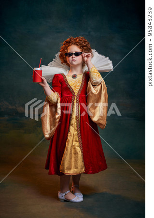 Portrait of little red-headed girl in costume of royal person posing in sunglasses and soda isolated over dark green background Portrait of little red-headed girl in costume of royal person posing in sunglasses and soda isolated over dark green background 95843239