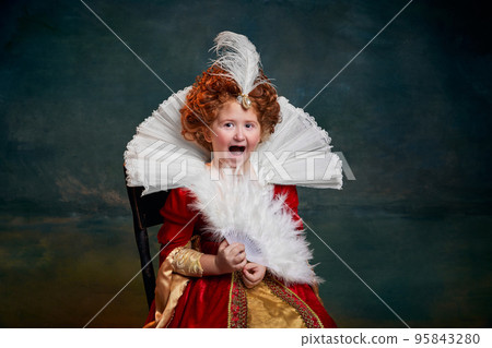 Portrait of little red-headed girl, child in costume of royal person laughing isolated over dark green background Portrait of little red-headed girl, child in costume of royal person laughing isolated over dark green background 95843280