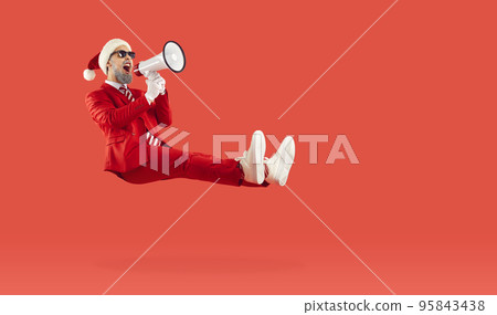 Happy man floating on red background, advertising Christmas sale and screaming through megaphone 95843438