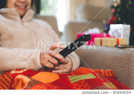 Asian elderly hand holding remote watching tv movie in living room on Christmas holidays 95844034