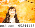 一個女人一邊欣賞秋葉一邊欣賞它們 95844138