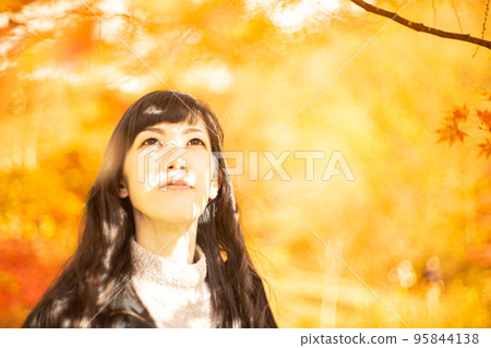 一個女人一邊欣賞秋葉一邊欣賞它們 95844138