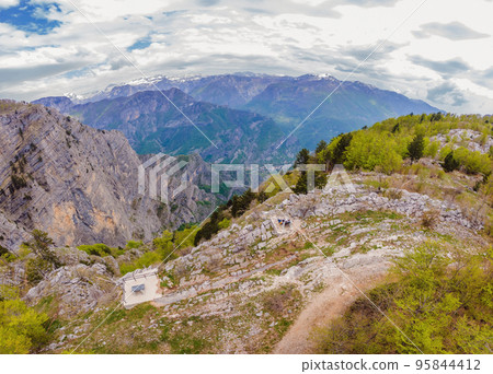 Happy family on background of Breathtaking panoramic view of the Grlo Sokolovo gorge in Montenegro. In the foreground is a mountain, the flat side of which forms a cliff, and the ridge is overgrown 95844412