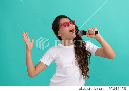 Happy kid singer sing karaoke song to microphone blue background, music 95844458