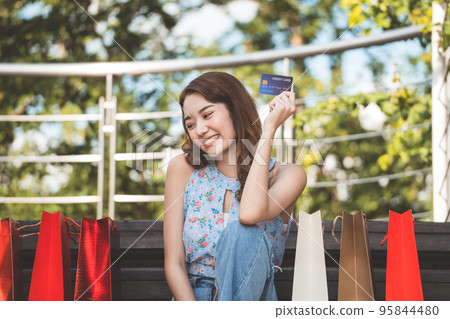 Young adult asian woman holding credit card and shopping bags. Young adult asian woman holding credit card and shopping bags. 95844480