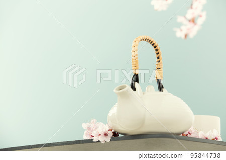 Cute teapot and spring cherry branches on blue background, copy space 95844738