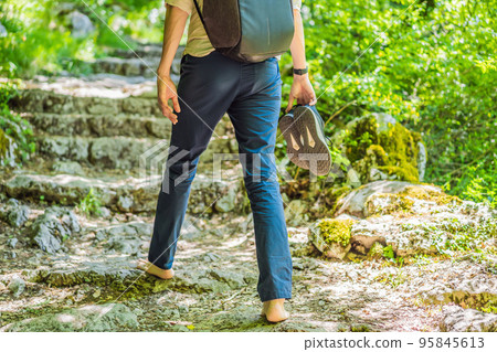 Man tourist climb barefoot the mountain to the Ostrog. It is a tradition to climb barefoot. Monastery of Ostrog, Serbian Orthodox Church situated against a vertical background, high up in the large Man tourist climb barefoot the mountain to the Ostrog. It is a tradition to climb barefoot. Monastery of Ostrog, Serbian Orthodox Church situated against a vertical background, high up in the large 95845613