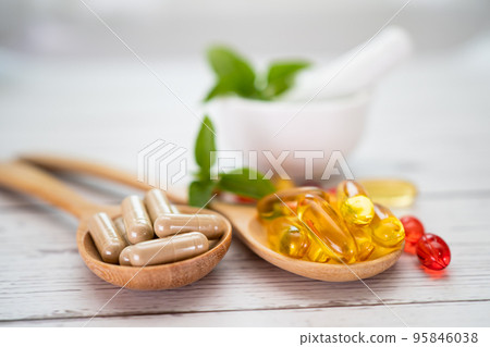 Vitamin C pills and vitamin E omega 3 fish oil on wooden spoon for good health. Vitamin C pills and vitamin E omega 3 fish oil on wooden spoon for good health. 95846038