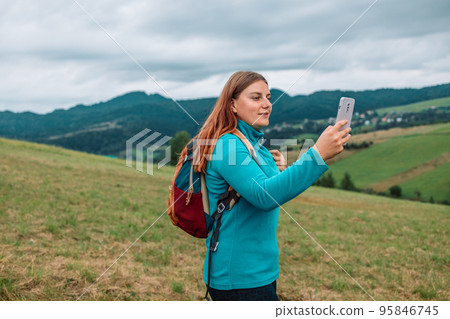 Pretty traveling woman standing on top of mountain and using mobile phone, hiking summer outdoors enjoys leisure on nature. Pretty traveling woman standing on top of mountain and using mobile phone, hiking summer outdoors enjoys leisure on nature. 95846745
