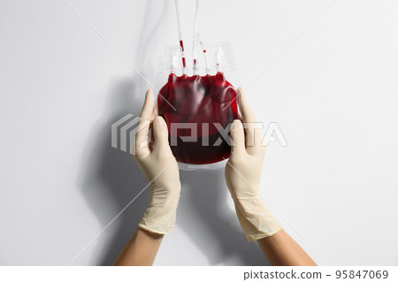 Woman holding blood for transfusion on light background, closeup. Donation concept 95847069
