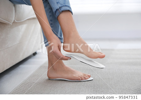 Woman fitting orthopedic insole at home, closeup Woman fitting orthopedic insole at home, closeup 95847331