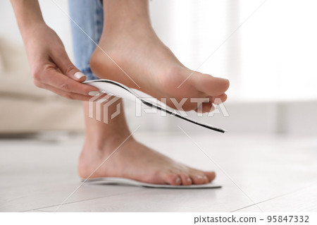 Woman fitting orthopedic insole at home, closeup 95847332