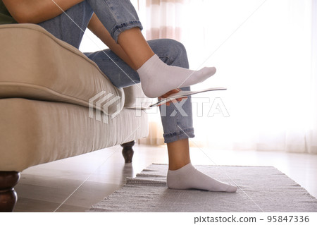 Woman fitting orthopedic insole at home, closeup 95847336