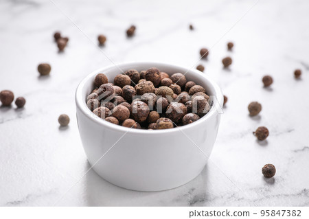 Black peppercorns in bowl on white marble table Black peppercorns in bowl on white marble table 95847382