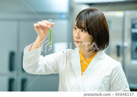 A woman in a white coat doing research 95848137