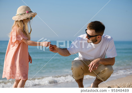 Father and daughter collect sea shells at beach Father and daughter collect sea shells at beach 95848489