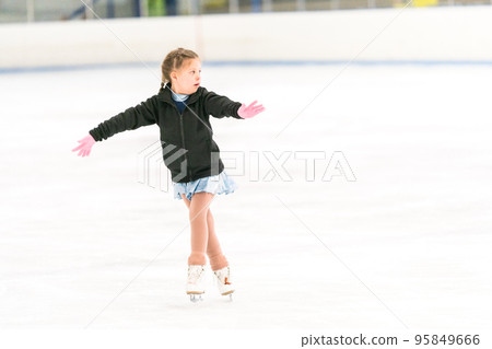 Little girl practicing figure skating on an indoor ice skating rink. Little girl practicing figure skating on an indoor ice skating rink. 95849666
