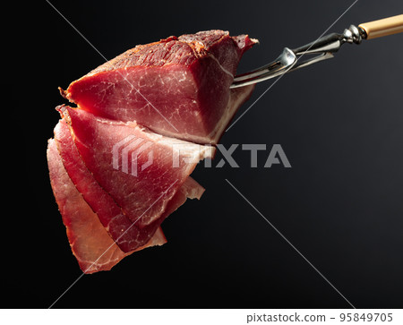 Dry-cured pork fillet on a black background. Dry-cured pork fillet on a black background. 95849705