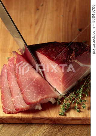 Dry-cured pork with thyme on a wooden cutting board. 95849706