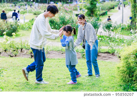 Girl and parents playing in the park 95850207
