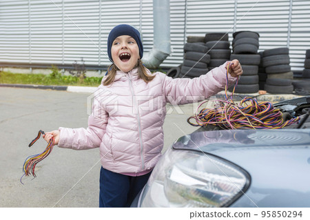 Happy girl works in a car garage of a car service center. Auto repair concept Happy girl works in a car garage of a car service center. Auto repair concept 95850294