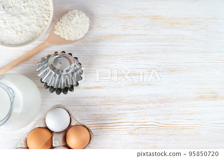 Baking ingredients flour, eggs, milk, bakeware on white wooden background with copy space 95850720