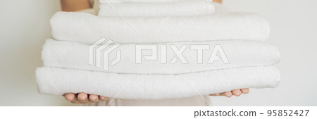 A woman is holding a stack of white towels. Concept of service in hotels, laundry, spa BANNER, long format 95852427