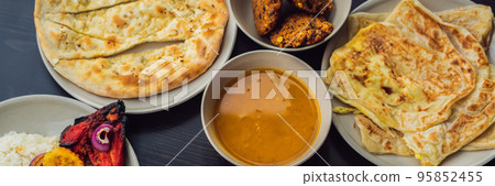 Assorted indian food on dark wooden background. Dishes and appetizers of indian cuisine. Curry, butter chicken, rice, lentils, paneer, samosa, naan, chutney, spices. Bowls and plates with indian food 95852455