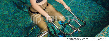 Young woman on bicycle simulator underwater in the pool BANNER, long format 95852456