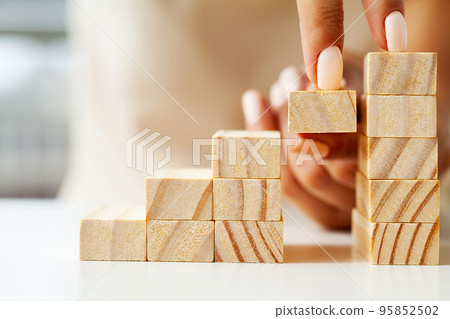 Woman hand arranging wood block stacking as step stair. Woman hand arranging wood block stacking as step stair. 95852502