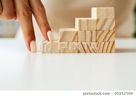 Woman hand arranging wood block stacking as step stair. Woman hand arranging wood block stacking as step stair. 95852504