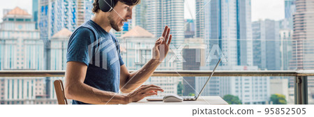 Young man teaches a foreign language or learns a foreign language on the Internet on her balcony against the backdrop of a big city. Online language school lifestyle BANNER, long format 95852505