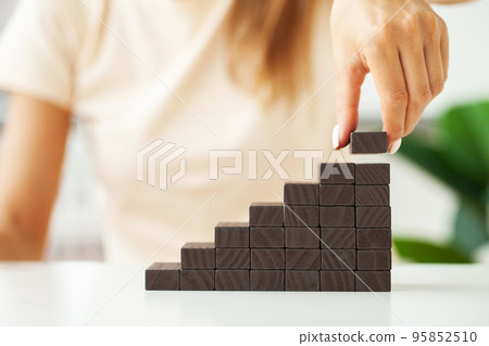 Woman hand arranging wood block stacking as step stair. Woman hand arranging wood block stacking as step stair. 95852510