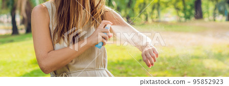 Woman spraying insect repellent on skin outdoor BANNER, long format 95852923