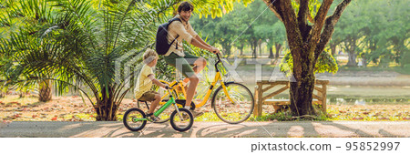 Happy family is riding bikes outdoors and smiling. Father on a bike and son on a balancebike BANNER, long format 95852997