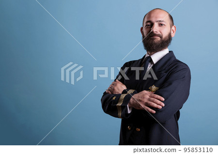 Airplane captain wearing uniform portrait standing with crossed arms, confident plane aviator looking at camera, studio medium shot. Serious civil pilot with badge on professional suit Airplane captain wearing uniform portrait standing with crossed arms, confident plane aviator looking at camera, studio medium shot. Serious civil pilot with badge on professional suit 95853110