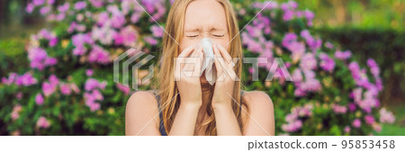 BANNER Pollen allergy concept. Young woman is going to sneeze. Flowering trees in background long format BANNER Pollen allergy concept. Young woman is going to sneeze. Flowering trees in background long format 95853458
