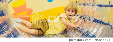 Cute little boy, playing in Zorb a rolling plastic cylinder ring with a hole in the middle, intdoor BANNER, long format 95853474