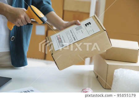 Young entrepreneur scanning online order box. Young entrepreneur scanning online order box. 95855179