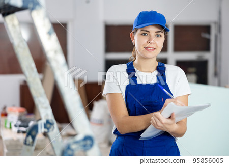 Smiling young female foreman making task list at construction site 95856005