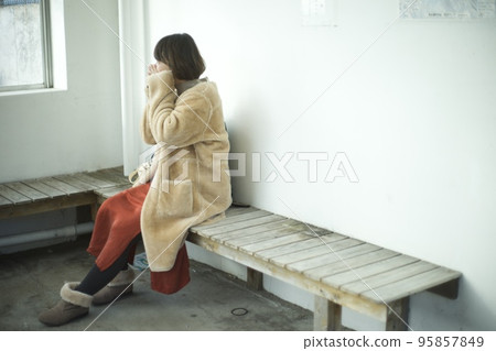 一名身穿大衣的女士在巴士候車室暖手 一名身穿大衣的女士在巴士候車室暖手 95857849