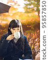 一位女士在露台上的咖啡館喝茶，露台上有美麗的秋葉 95857850